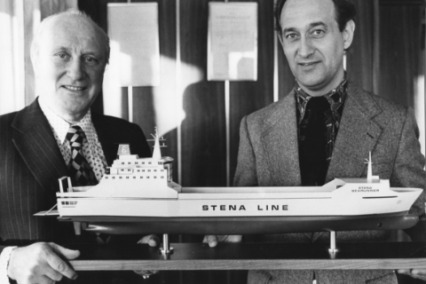Two men standing in front of a vessel model